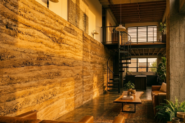 Parede de argila estabilizada em loft urbano com concreto aparente e iluminação natural